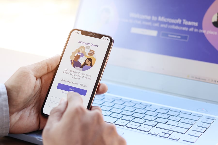 City employee opening Microsoft Teams on a phone while working at a laptop